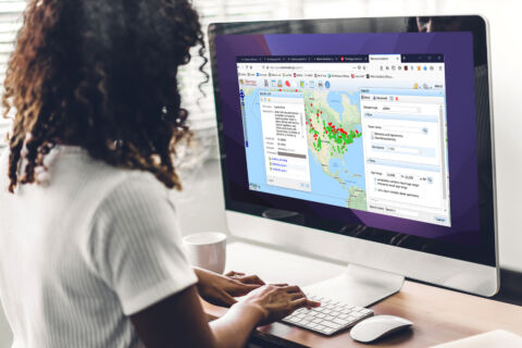 A woman standing in front of a large monitor with Neotoma Explorer data interface on her monitor